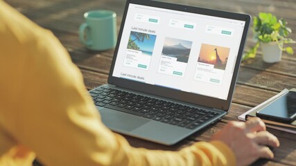 planning vacation at computer,back view of male browsing holiday offers on laptop,last minute trip deal on internet website