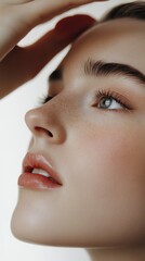 Canvas Print - Close-up portrait of a young woman with freckles, looking up with her hand on her forehead.