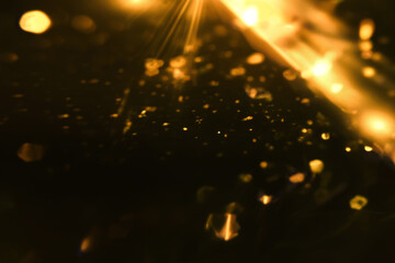 Wall Mural - Golden blurred bokeh lights overlay on black background. Glitter sparkle stars Golden blurred bokeh lights overlay on black background. Glitter sparkles light effect