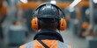 © Wannaeka - Person in orange hard hat and headphones standing in industrial