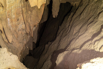 A cave with a dark tunnel. The tunnel is narrow and has a lot of dirt.