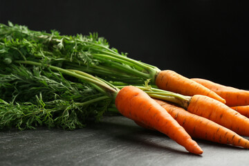 Wall Mural - Tasty ripe juicy carrots on dark gray textured table, closeup