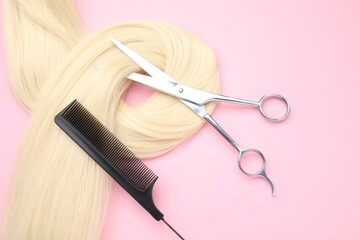 Wall Mural - Blonde hair strand, comb and professional scissors on pink background, top view