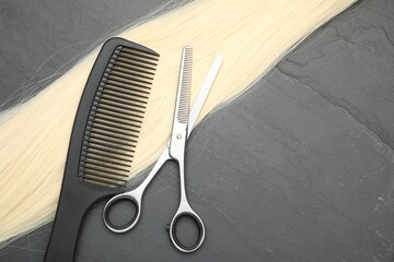 Wall Mural - Blonde hair strand, comb and professional scissors on grey surface, flat lay. Space for text