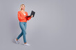 © deagreez - Full size profile photo of pretty young girl walk laptop empty space isolated on grey color background