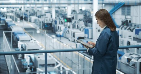 Aufkleber - Young Asian Female Engineer Standing on a Platform, Using Tablet Computer at an Electronics Factory. Machines are Undergoing Maintenance, Specialist Monitoring the Progress Through Online Software