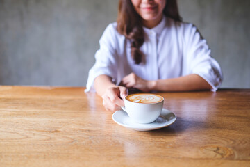 Canvas Print - Closeup image of a young woman holding and drinking hot coffee