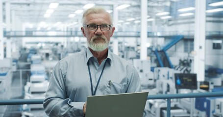 Aufkleber - Portrait of a Handsome Middle Aged Engineer with a Beard and Glasses Using Laptop Computer and Looking at Camera. Male Specialist Working in a Modern Electronics Factory
