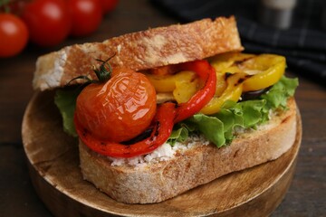 Tasty sandwich with grilled vegetables and cream cheese on wooden table, closeup