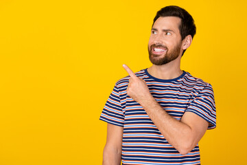 Wall Mural - Portrait of nice guy with stylish bristle wear striped t-shirt indicating look at offer empty space isolated on yellow color background