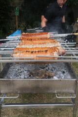 Rolled joints of pork being cooked over charcoal outdoors