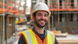 © VikaKa - A smiling construction worker, clad in a hard hat and a high-visibility vest, poses for a portrait at a construction site