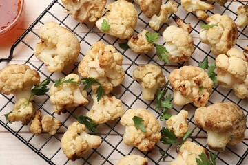 Poster - Cooling rack with tasty baked cauliflower and parsley on light wooden table, top view