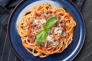 Canvas Print - Delicious pasta bolognese with basil on black table, top view