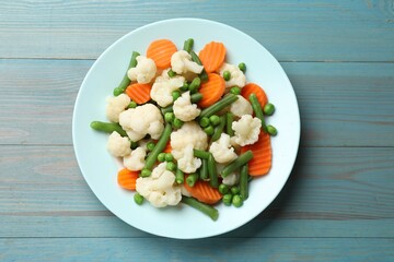 Poster - Tasty cooked cauliflower with green peas, string beans and carrot slices on light blue wooden table, top view