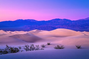 Wall Mural - A serene desert landscape at dusk with soft sand dunes and distant mountains under a colorful sky.