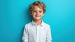 © Pixel Mind - A young boy stands smiling against a vibrant turquoise backdrop, exuding happiness and charm in a classic white shirt