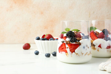 Wall Mural - Tasty yogurt with fresh berries, granola and mint in glasses on white marble table, space for text