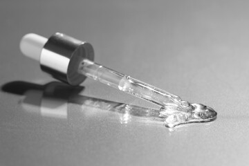 Poster - Dripping cosmetic serum from pipette on grey background, closeup