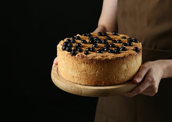 Canvas Print - Woman with delicious homemade blueberry pie on black background, closeup