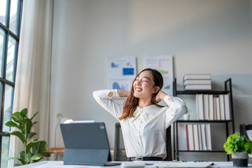 Wall Mural - young asian businesswoman stretching at workplace in office after work is done