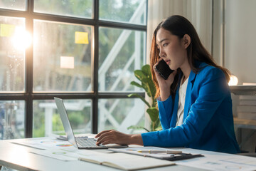 Wall Mural - businesswoman talking on phone and working on laptop in office