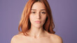 © Andrii Nekrasov - Close-up of red-haired woman looking at camera on purple background. Beautiful girl poses in studio with blank space on violet wall for your promotion