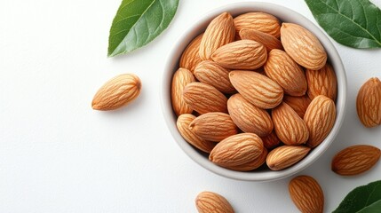 Close-up of a bowl of almonds with green leaves on a white background.