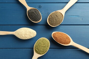 Wall Mural - Different superfood powders in spoons on blue wooden table, above view