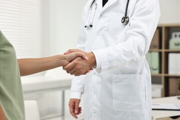 Wall Mural - Doctor shaking hands with patient in hospital, closeup