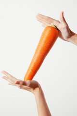 Poster - Person holding an orange carrot in one hand with the other hand on the opposite side