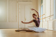 © Юлия Завалишина - Young ballerina in tutu skirt stretching practicing ballet positions dancing in dance class. Young classical dancer woman in dance studio. Ballet class training Ballet school concept