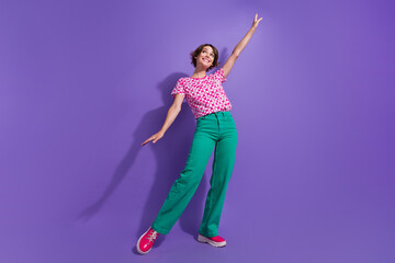 Canvas Print - Full length photo of adorable girl dressed green pants hold arm up dreamy look at discount empty space isolated on purple color background