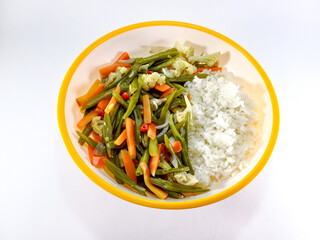 Stir-fried vegetables including green beans, carrots, cauliflower, and onions, served with rice on a plate with an orange accent, against a white background, presenting a vibrant and wholesome meal