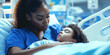 © Lila Patel - Nurturing African American woman in scrubs, comforting sick child in hospital room.