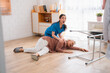 © chokniti - senior patient falling on the ground floor at home, Asian caregiver helping elderly older female from accident after doing physical therapy then rescued by attractive therapist nurse, health insurance