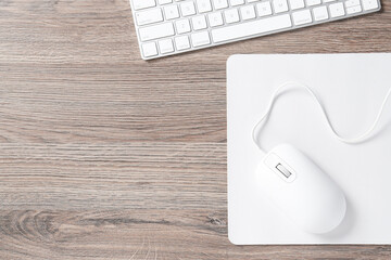 Wall Mural - Computer mouse with mousepad and keyboard on wooden desk, top view. Space for text