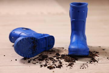 Canvas Print - Rubber boots with mud on wooden floor