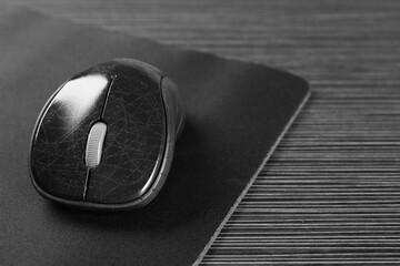 Wall Mural - Computer mouse with mousepad on black wooden table, closeup. Space for text