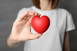 © New Africa - Woman holding red heart on grey background, closeup