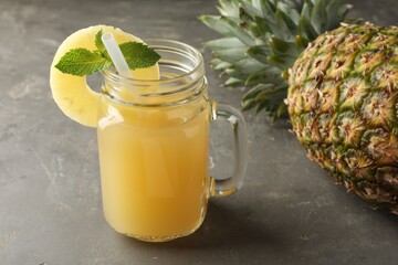 Canvas Print - Tasty pineapple juice in mason jar, mint and fruit on grey textured table, closeup