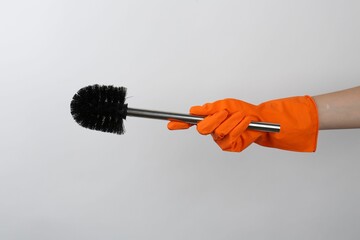 Wall Mural - Woman holding black toilet brush on light background, closeup. Cleaning tool