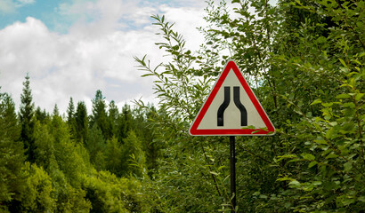 road signs warning of narrowing of the road, on a dirt road