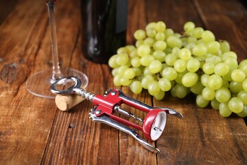 Wall Mural - Wing corkscrew, cork and grapes on wooden table, closeup