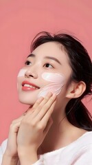 Canvas Print - Smiling Asian Woman Applying Face Mask On Pink Background