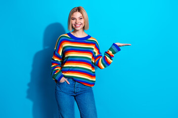 Portrait of pretty young girl arm show empty space wear striped pullover isolated on blue color background