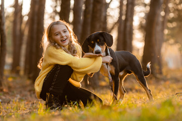 little teenage girl walks with her dog in the autumn in the forest