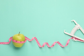 Poster - Body fat caliper, measuring tape and apple on turquoise background, flat lay. Space for text