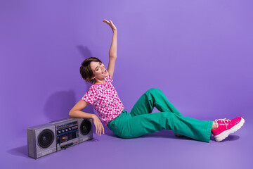 Wall Mural - Full length photo of adorable girl dressed stylish t-shirt sit with boombox hand up look empty space isolated on purple color background