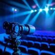© Pornarun - A professional video camera captures the empty seats in a theater illuminated by bright stage lights.